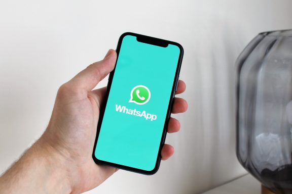Ein Handy mit dem WhatsApp-Logo auf blauer Hintergrundfarbe.